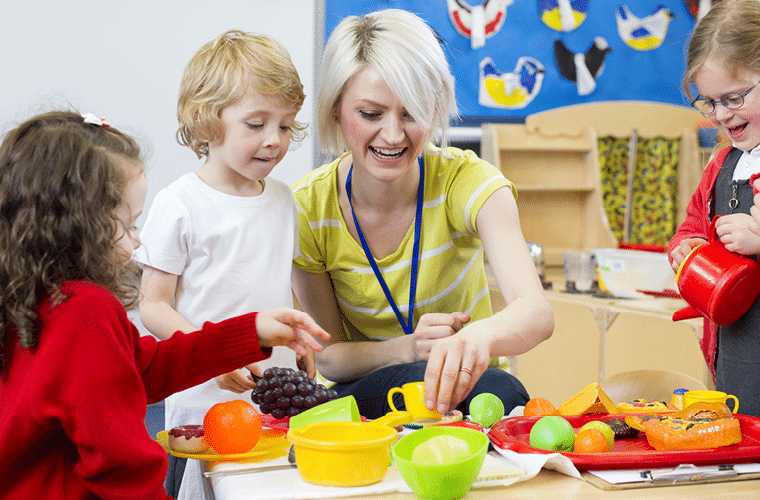young child working with a nursery assistant at a table
