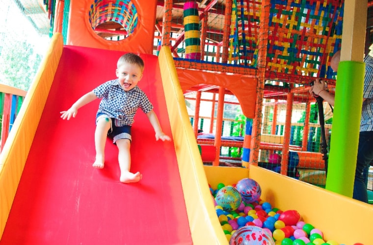 small child on a red slide ant a soft play centre